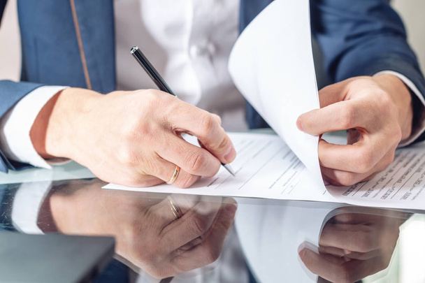 Бизнесмен, сидящий за столом, подписывает документы в офисе крупным планом. Концепция регистрации сделок и работы с ценными бумагами
 - Фото, изображение