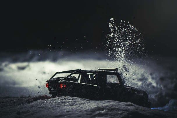 Radio-controlled car in the snow at night, lights shine. Christmas entertainment gift rc car. - Photo, Image