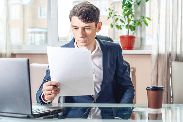 Bir iş yerinde incelenirken belgeleri oturan erkek iş adamı. Office belgeleriyle çalışma kavramı - Fotoğraf, Görsel