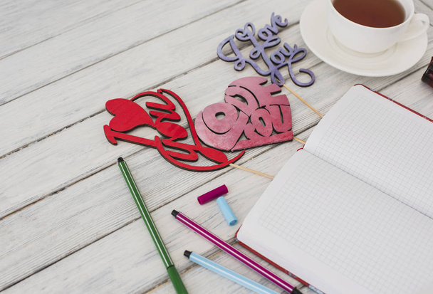 Valentin-nap. Notebook egy piros szív fehér fából készült asztal. Romantikus reggel a szerelmesek napján. Szemközti nézet - Fotó, kép