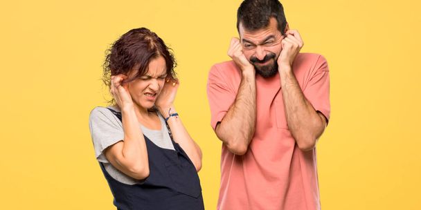 Paar mit schwangeren Frauen, die Ohren mit Händen bedecken. Frustrierter Ausdruck auf gelbem Hintergrund - Foto, Bild
