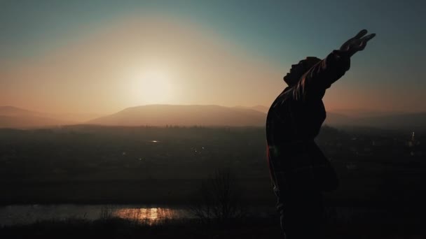 Die Silhouette des Menschen hebt die Hände, wenn er im Sonnenuntergang auf dem Berg steht. Freiheitskonzept - Filmmaterial, Video