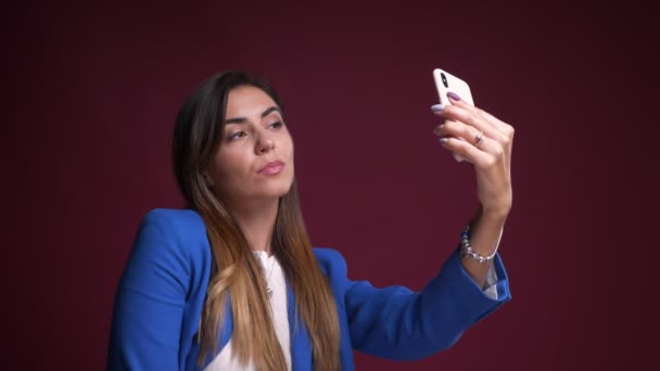 Closeup portrait of attractive caucasian female taking selfies on the phone and smiling in front of the camera - Materiał filmowy, wideo