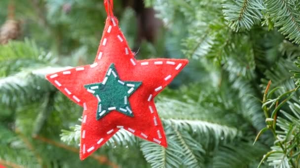 Christmas tree toy in the shape of star of red color from wool fabric decorated with glass beads that hangs on a branch - Footage, Video