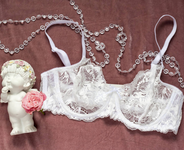 white lace bra on pink velvet background and angel with rose - Photo, Image