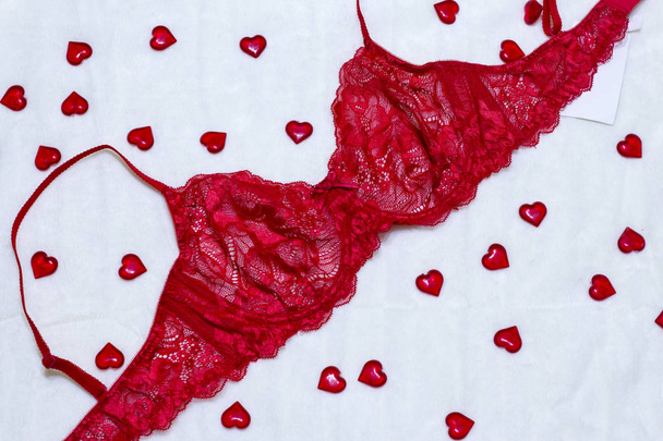 Romanttiset alusvaatteet ystävänpäivän houkutukseksi. punainen pitsi rintaliivit valkoisella taustalla sydämet
 - Valokuva, kuva