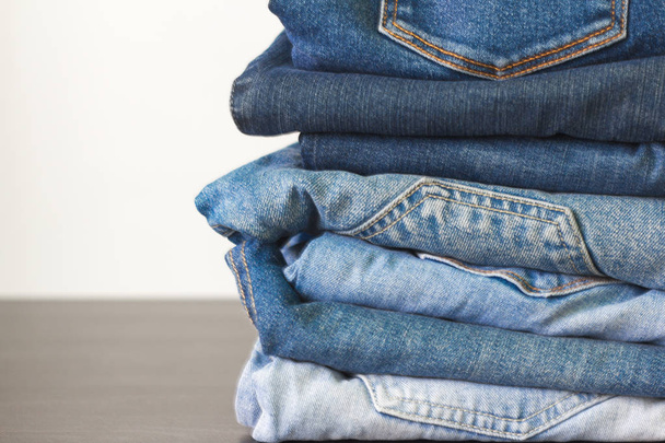 stack of blue jeans of different shades on the table - Photo, Image
