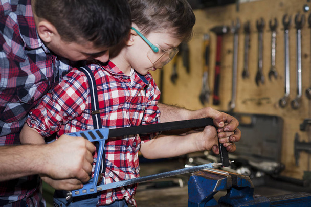 father took his little son to work with metal. Concept of relationship, child at work turner - 写真・画像