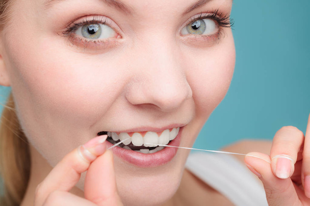 Mundhygiene und Gesundheitsfürsorge. Lächelnde Frauen verwenden Zahnseide weiße gesunde Zähne. - Foto, Bild