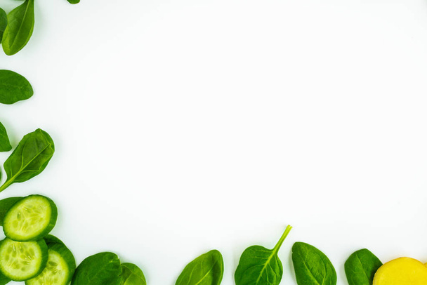 frischer grüner Blattspinat, Gurkenscheiben und Ingwer isoliert auf weißem Hintergrund. Gemüse am Bildrand mit Kopierraum für Text. gesundes und entgiftendes Konzept - Foto, Bild