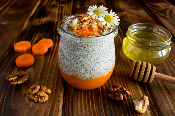 Pudding with chia,carrot,walnuts  and honey on the brown  wooden background - Photo, Image
