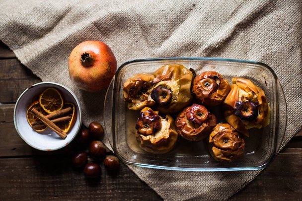 Roasted apples in a glass tray with chestnuts, cinnamon, orange and pomegranate - Φωτογραφία, εικόνα