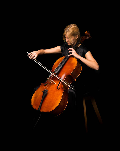 junges Mädchen spielt Cello auf isoliertem schwarzen Hintergrund - Foto, Bild