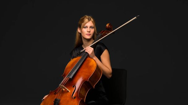 Giovane ragazza che suona il violoncello su sfondo nero isolato
 - Foto, immagini