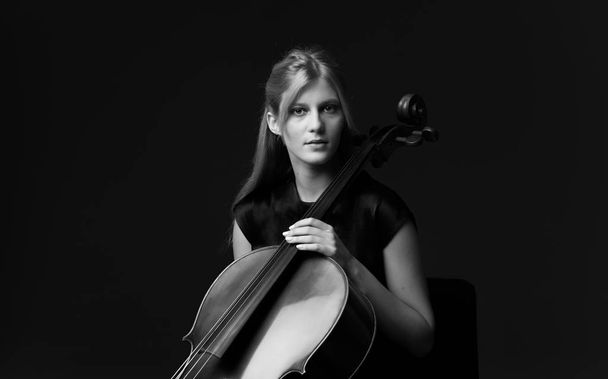 Mladá dívka si hraje na violoncello na izolované černém pozadí - Fotografie, Obrázek