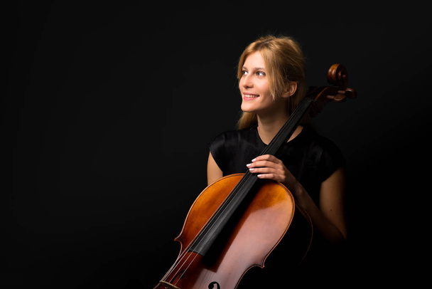 junges Mädchen spielt Cello auf isoliertem schwarzen Hintergrund - Foto, Bild