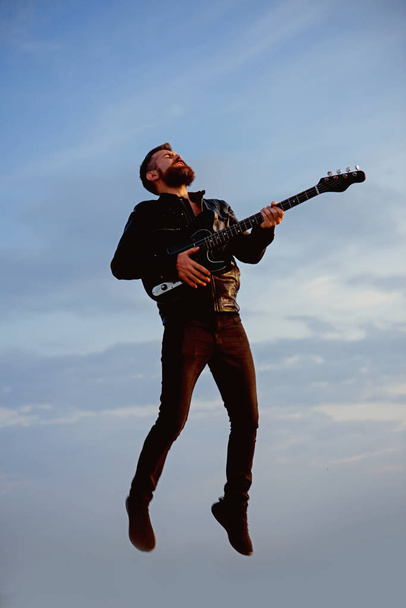 Music and freedom make him happy. Music, bearded hipster play guitar flying in blue sky - Zdjęcie, obraz