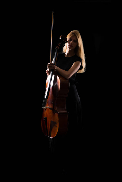 Молода дівчина грає на віолончелі на ізольованому чорному тлі
 - Фото, зображення