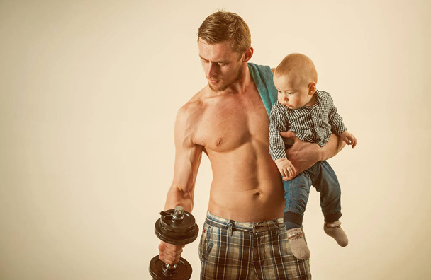 Healthy family lifestyle. Strong man with dumbbells hold baby boy. Father build biceps triceps with son. Father and child training together. Active family enjoy sport and fitness. Energy and power - Valokuva, kuva