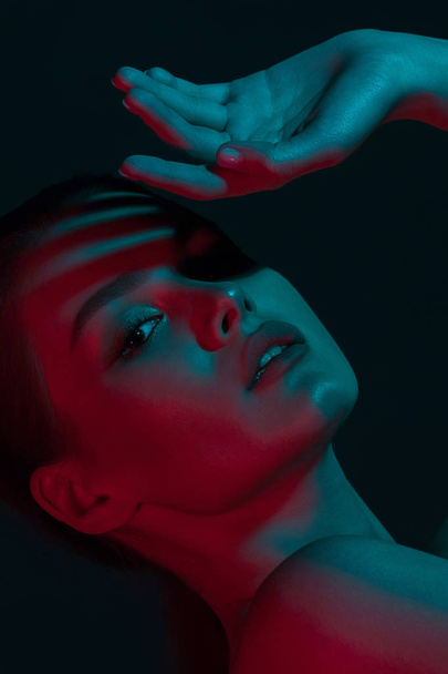 Young beautiful girl with blue and red neon lighting. Beauty close-up portrait - 写真・画像