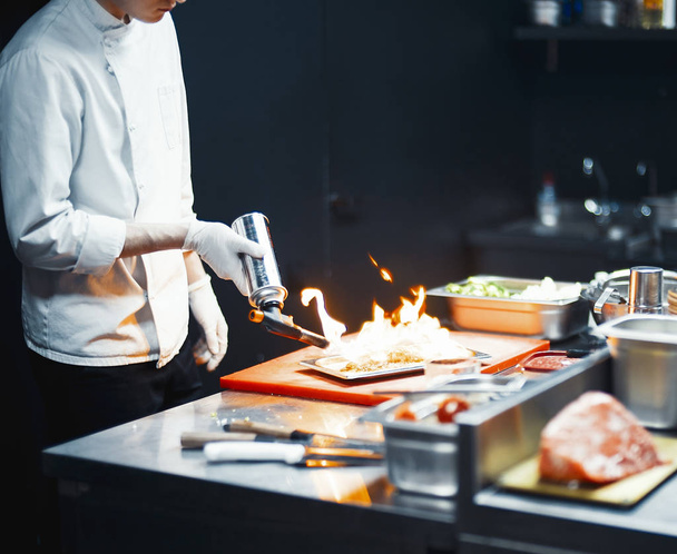 Restaurant Chef cook preparing salmon filet flambe in open kitchen. - Valokuva, kuva