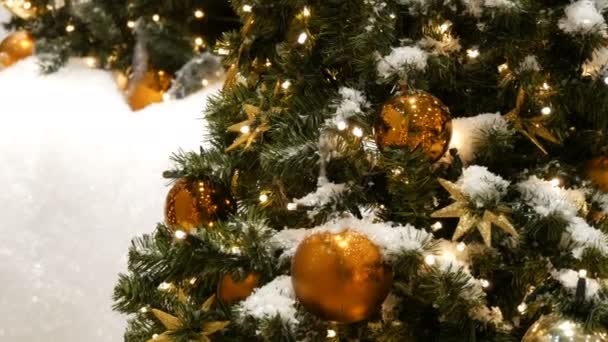 Красиво прикрашена ялинка з великими золотими і срібними кульками, зірками, гірляндами і штучним снігом стоїть в торговому центрі крупним планом
 - Кадри, відео