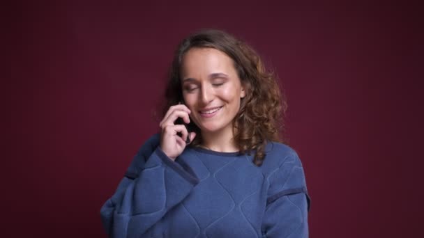 Closeup portrait of young cheerful caucasian female talking on the phone and smiling happily - Кадри, відео