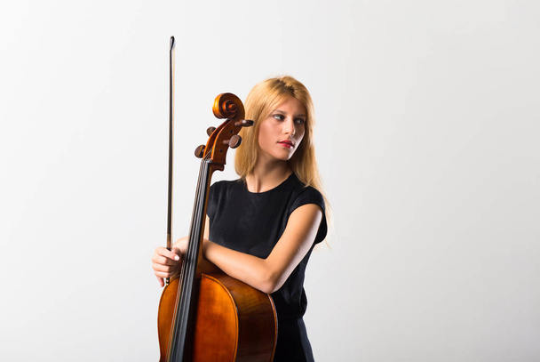 Mladá blondýnka s cello pózuje na bílé zdi - Fotografie, Obrázek