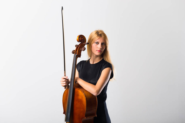 Mladá blondýnka s cello pózuje na bílé zdi - Fotografie, Obrázek