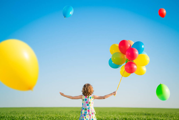 Menina brincando com balões multicoloridos brilhantes ao ar livre
.  - Foto, Imagem