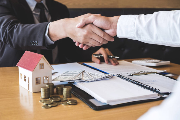 Образ успешной сделки с недвижимостью, брокер и клиент пожимают руку после подписания договора одобренной анкеты, касающейся предложения ипотечного кредита и страхования дома
. - Фото, изображение