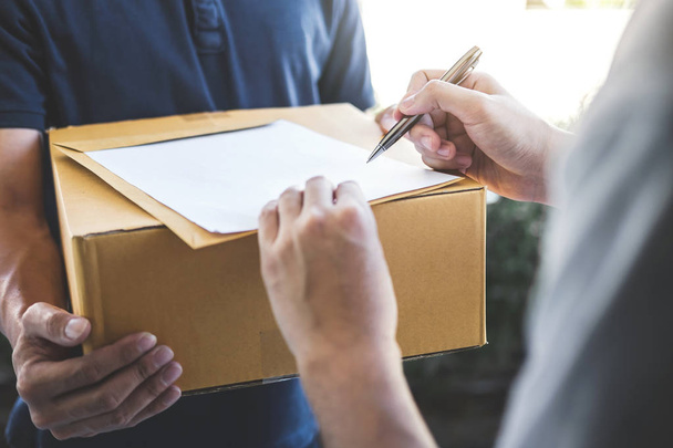 Postai kézbesítő csomagküldő doboz adva címzett és aláírás forma, fiatal tulajdonosának aláírása a szállítási csomag a postai szállítás futárral, a haza felszabadítás szolgáltatás és a szolgáltatás mind munka átvételekor. - Fotó, kép