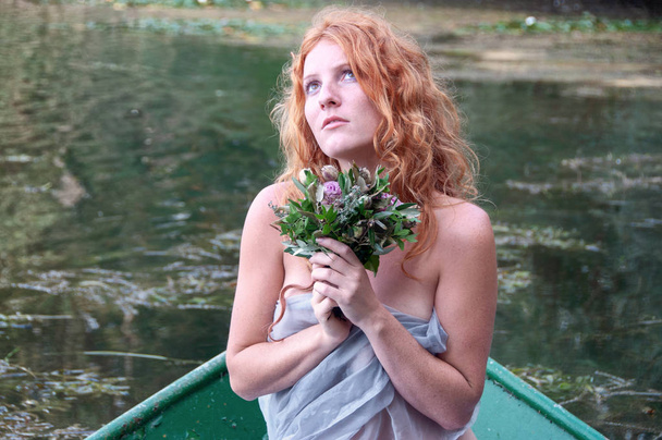 若く美しい放棄された女性、花嫁、シャロットの座って熱心に放棄されたボートと彼の死んだ最愛の人のための愛の完全な待機の花の花束と - 写真・画像