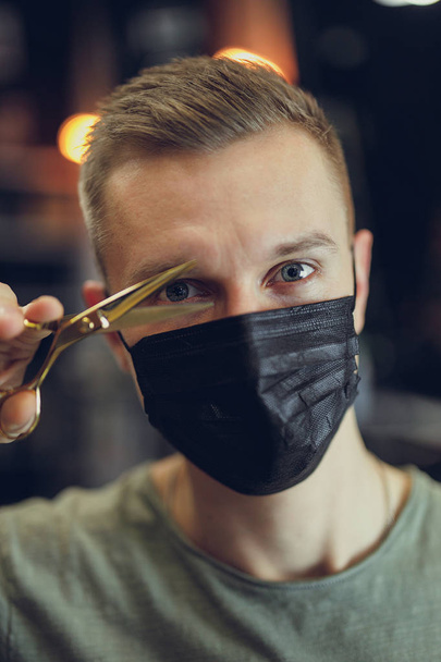 Hairdresser wear mask and hold scissors near his face. - Image - Photo, Image