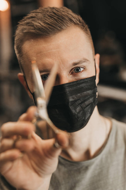 Hairdresser wear mask and hold scissors near his face. - Image - Φωτογραφία, εικόνα