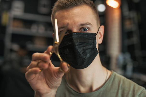 Hairdresser wear mask and hold scissors near his face. - Image - Fotoğraf, Görsel
