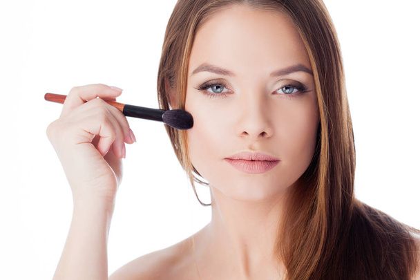 Use the powder. Attractive girl doing makeup. Portrait of a beautiful young woman using a brush for Foundation - Foto, Imagen