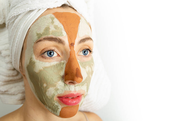 Procedimentos de beleza conceito de cuidados da pele. Mulher jovem aplicando máscara de barro cinza facial e lama vermelha em seu rosto no banheiro. Mulher com máscaras diferentes em seu rosto multi-mascaramento - Foto, Imagem