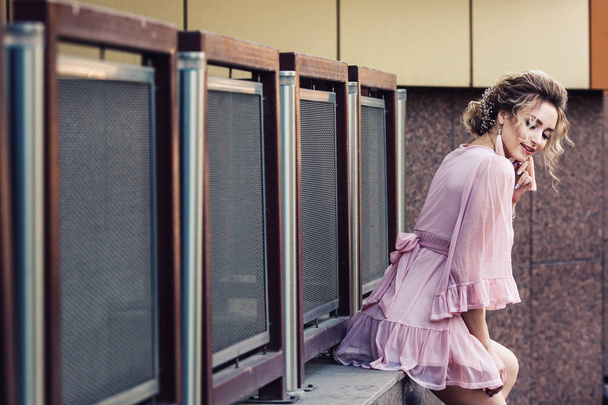 приваблива молода дівчина в короткій рожевій сукні позує біля красивої будівлі
. - Фото, зображення