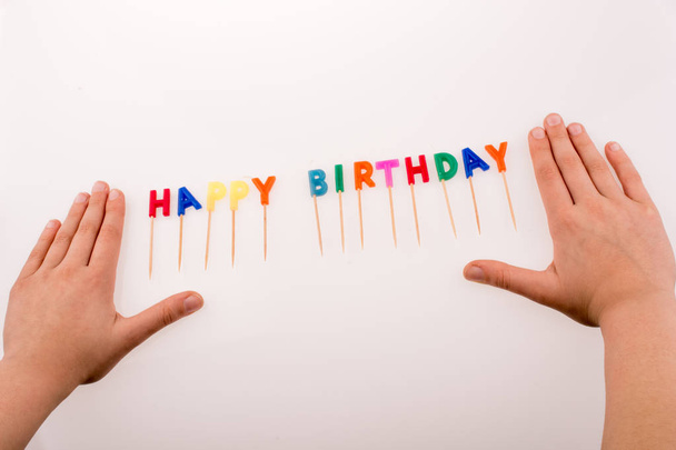 Hand and color candles on sticks write the words happy birthday - Photo, Image