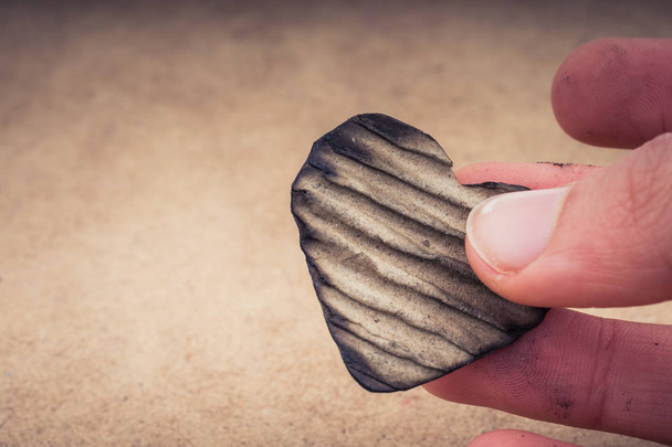 Hand met een hartvormig verbrand van een karton - Foto, afbeelding