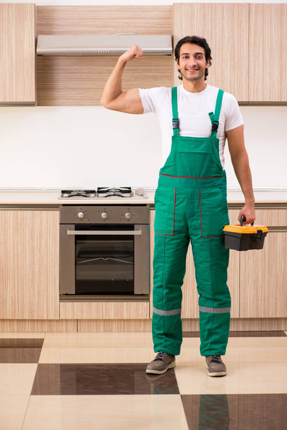 joven contratista reparación de horno en la cocina  - Foto, Imagen