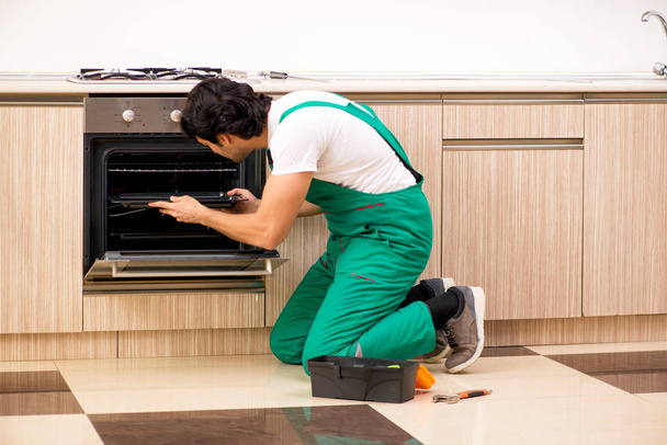 Genç müteahhit mutfakta fırın onarıyor.  - Fotoğraf, Görsel