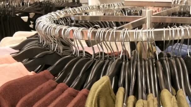 auf großen runden Kleiderbügeln hängen in einem Bekleidungsgeschäft in einem Einkaufszentrum oder Einkaufszentrum verschiedene stylische Strickpullover, Nahsicht - Filmmaterial, Video