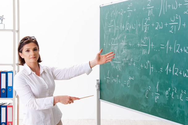 Θηλυκό μαθηματικά δάσκαλος μπροστά από το μαυροπίνακα  - Φωτογραφία, εικόνα