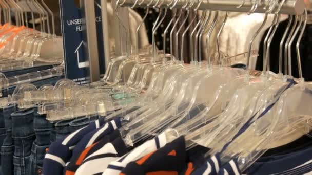 Erilaisia monivärisiä naisten vaatteita ja farkkuja roikkuu ripustimet vaatekaupassa ostoskeskuksessa tai ostoskeskuksessa
 - Materiaali, video