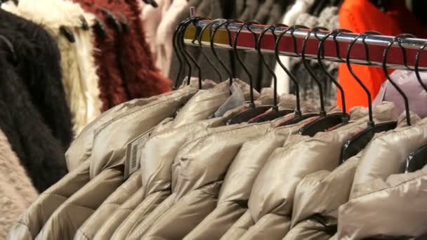 Verschillende womens winter jassen kleding hangen aan kledinghangers in een kledingwinkel in mall of shopping center - Video