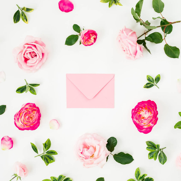 Floral composition of pink roses flowers and pink envelope on white background. Flat lay, top view. Valentines day - Photo, Image
