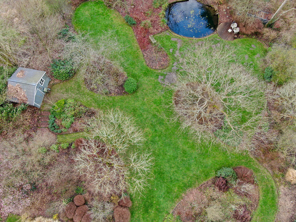 Widok z lotu ptaka piękny angielski ogród typu w sezonie zimowym. Piękny widok na piękny angielski ogród z dużą zieloną trawą, Funt trochę wody i mały ogród Dom z drewna. - Zdjęcie, obraz