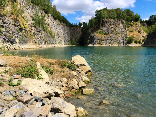 Quarry explored by scuba divers. Flooded quarry for adrenaline hobby. Diver site with fresh blue and clean crystal water with divers. Divers in the blue quarry during summer. Floreffe, Belgium. - Photo, Image